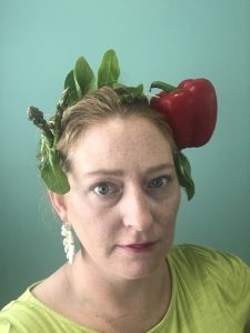 Laura Thompson wearing a hat made of a pepper, spinach, and asparagus